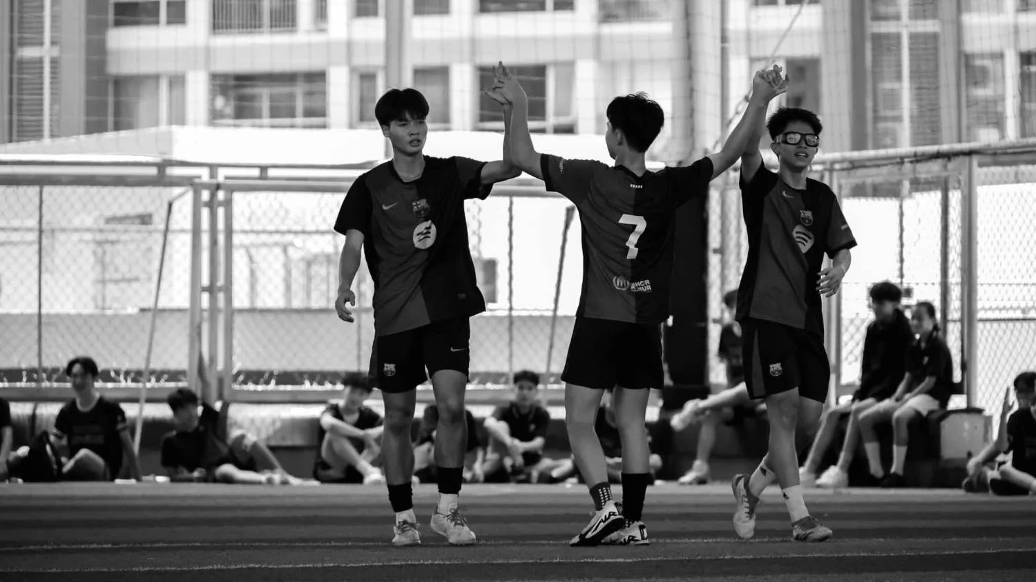 Toan, No. 7, high-fiving two teammates on the pitch, in black and white